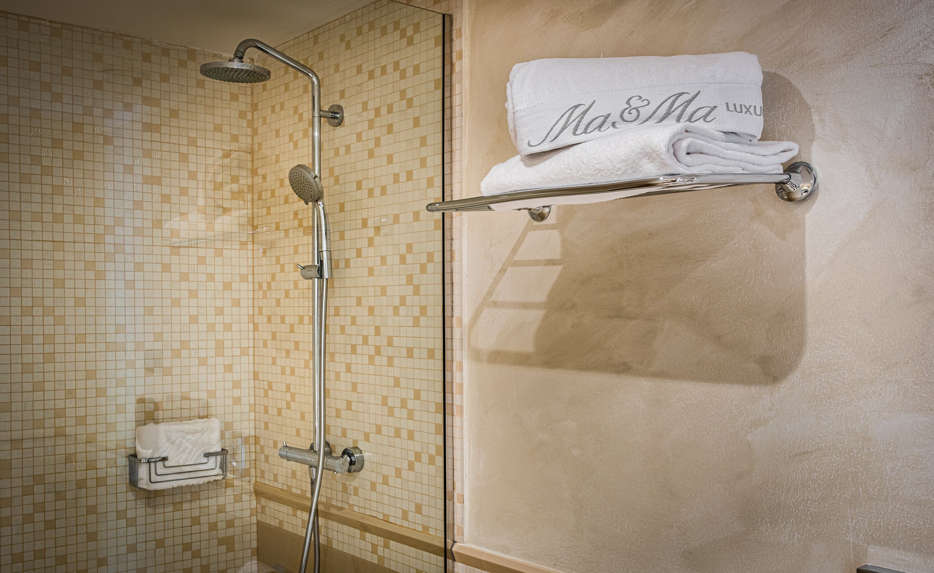 A bathroom with a shower, tiled walls, and a towel rack with a folded towel.