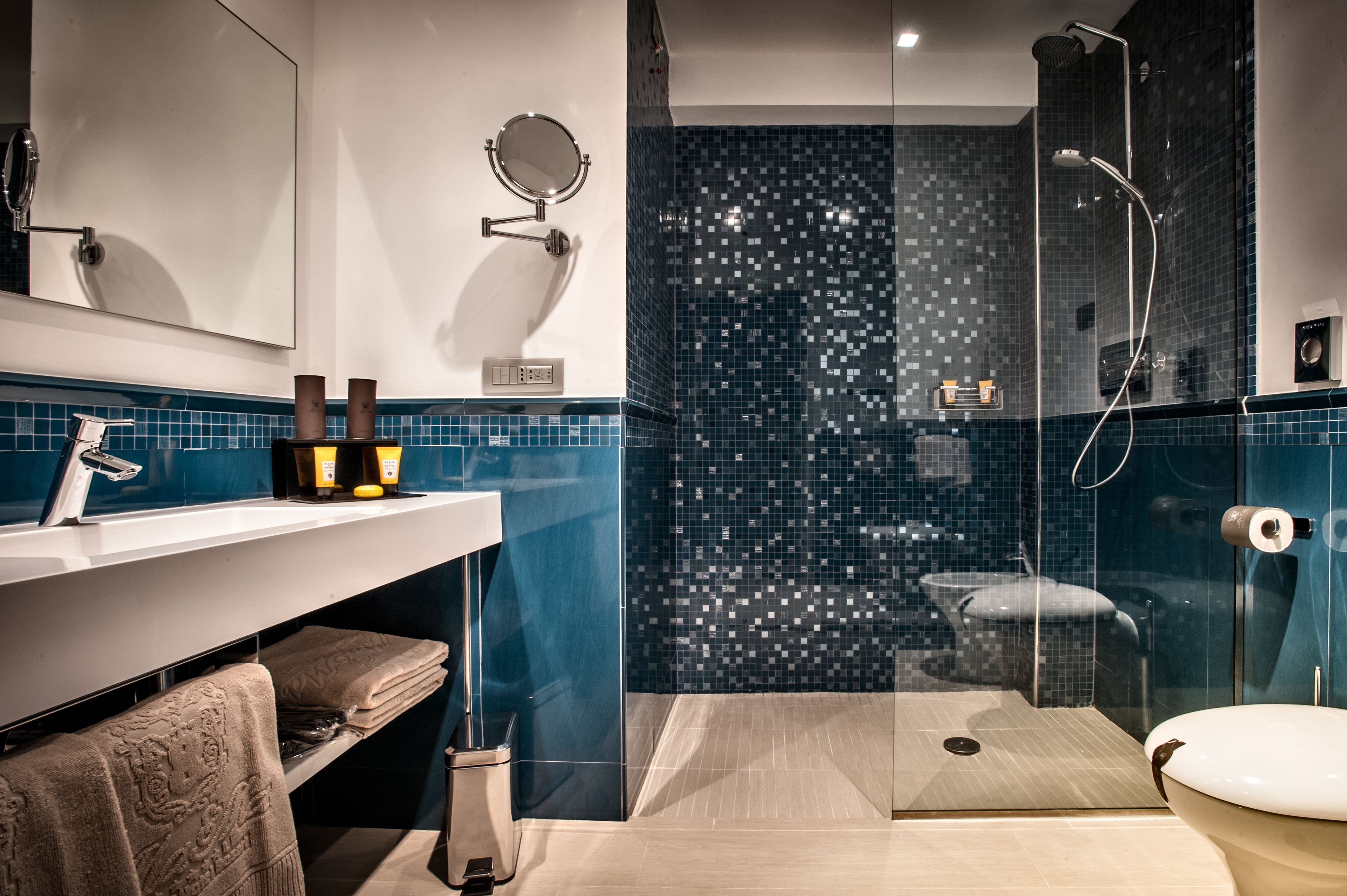 Un baño moderno con ducha envuelta en cristal, un lavabo blanco y un espejo.
