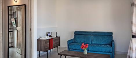 A modern living room with a blue sofa, a wooden coffee table, and a small cabinet.
