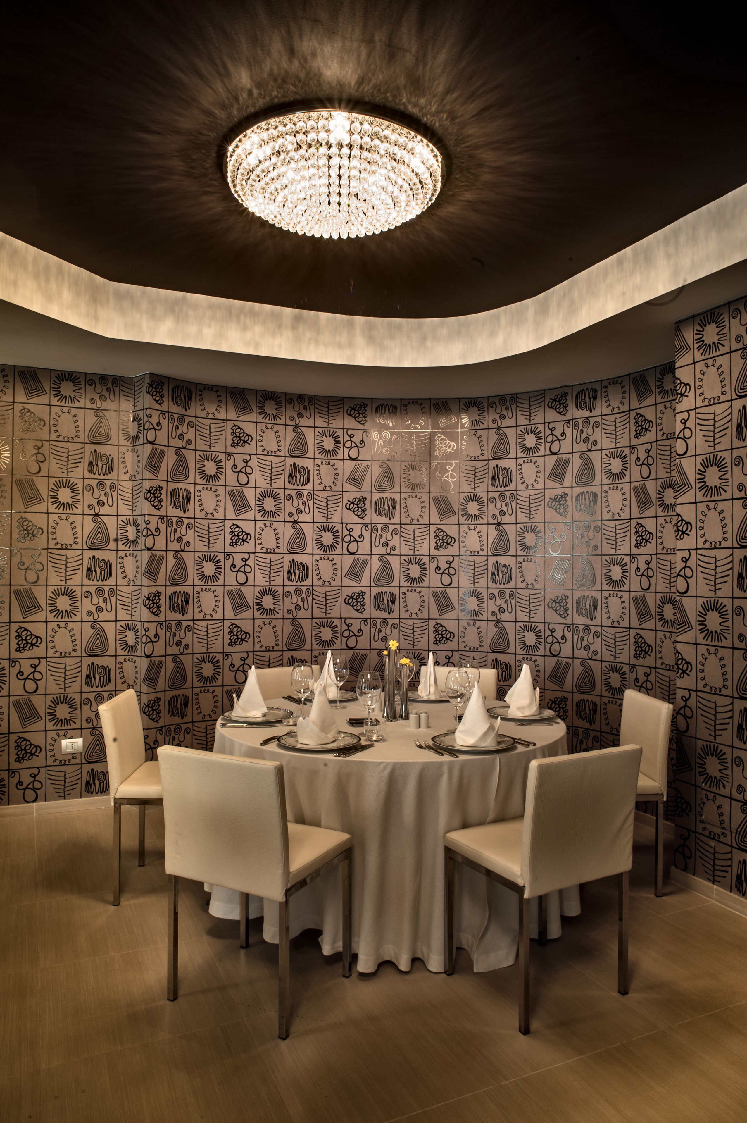 A dining area with a round table, chairs, and a chandelier.