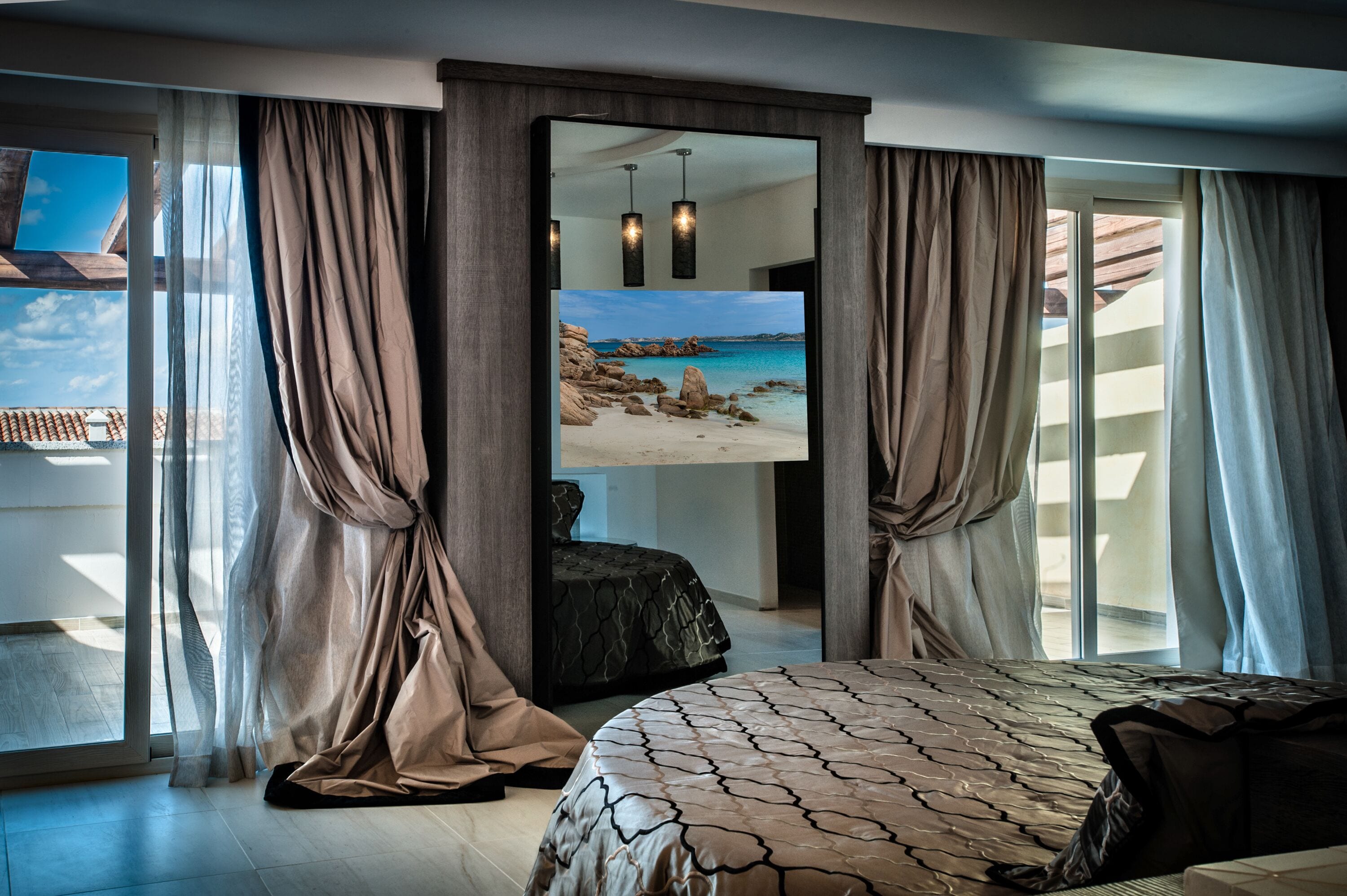 A bedroom with a large bed, a view of a beach through a sliding glass door, and a modern interior design.