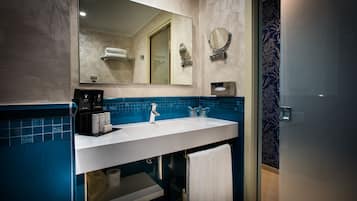Une salle de bain moderne avec un lavabo blanc, un pare-feu en carreaux bleus et un grand miroir.