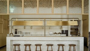 A kitchen with a marble countertop, wooden stools, and a glass backsplash.