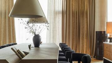 A modern dining area with a wooden table, black and white checkered rug, and a hanging light fixture.