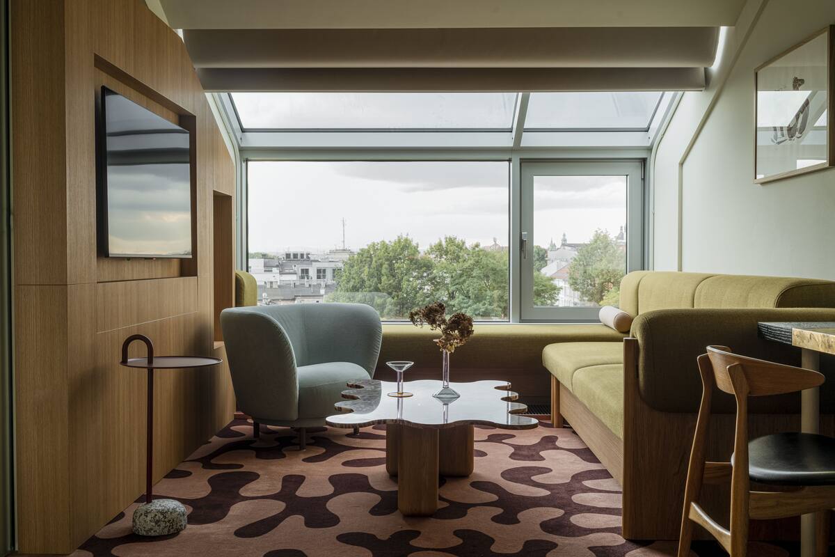 Een moderne woonkamer met een groot raam, een bank, een fauteuil en een salontafel met een vaas.