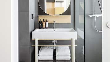 A modern bathroom with a white sink, a large mirror, and a glass-enclosed shower.