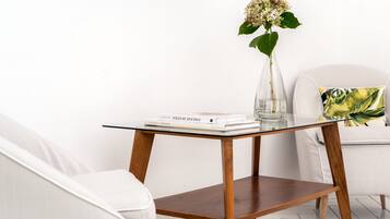 A modern room with a glass-top table, a white chair, and a white sofa.