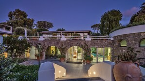 A modern building with a stone archway entrance, a covered outdoor area, and a large potted plant. - Botania Relais & Spa - The Leading Hotels of the World. (Forio)