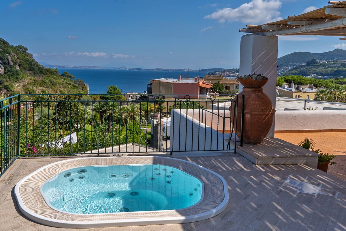 A hot tub on a balcony with a view of the sea and mountains.