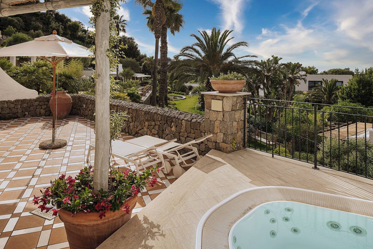 A patio area with a hot tub, outdoor furniture, and a stone wall.