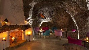 A cozy interior with a stone wall, wooden furniture, and candles providing warm lighting. - Botania Relais & Spa - The Leading Hotels of the World. (Forio)