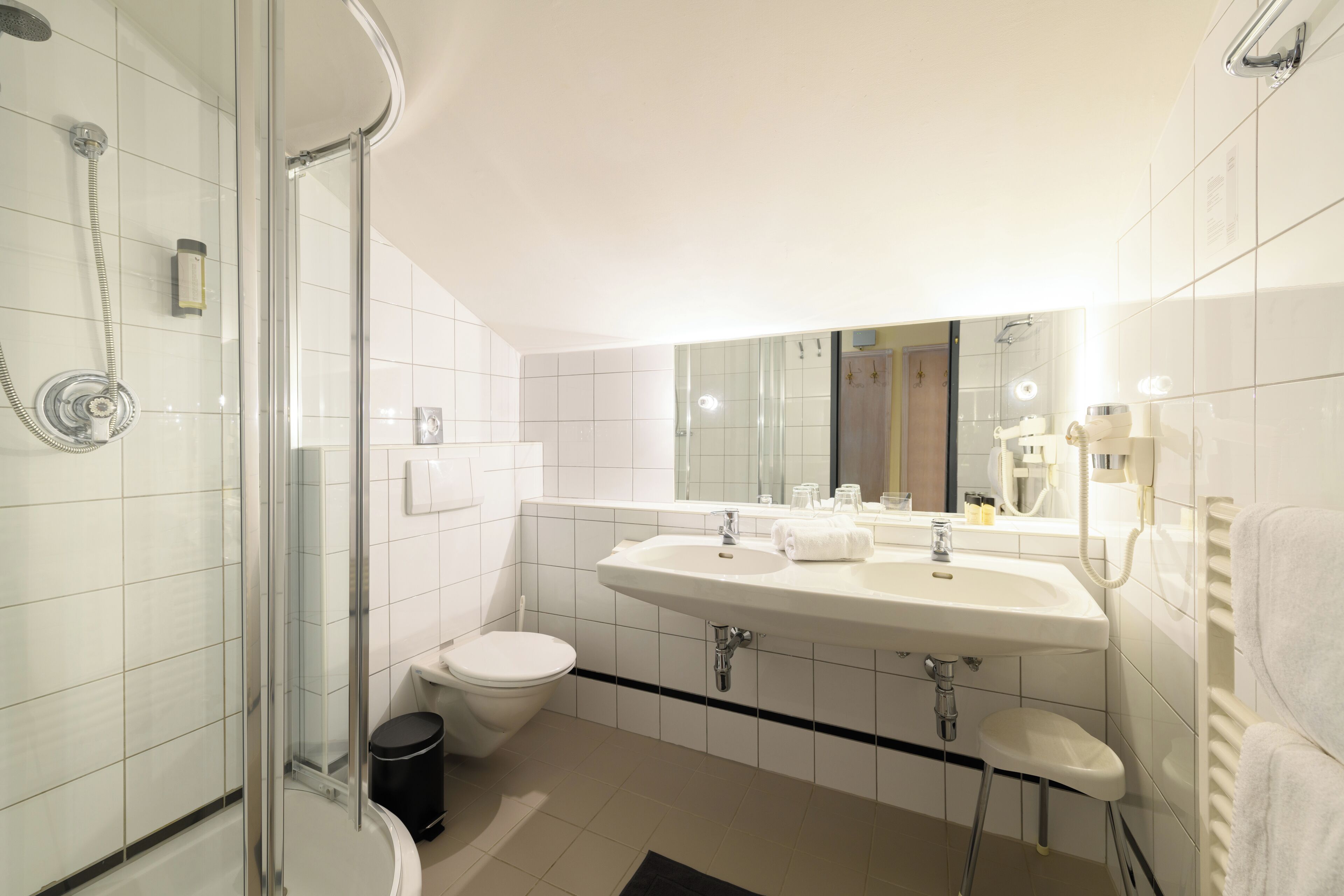 Une salle de bain moderne avec une douche à parois de verre, un lavabo blanc et des toilettes.