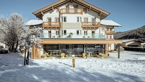 A large, multi-story hotel with a covered outdoor seating area and a snow-covered landscape.