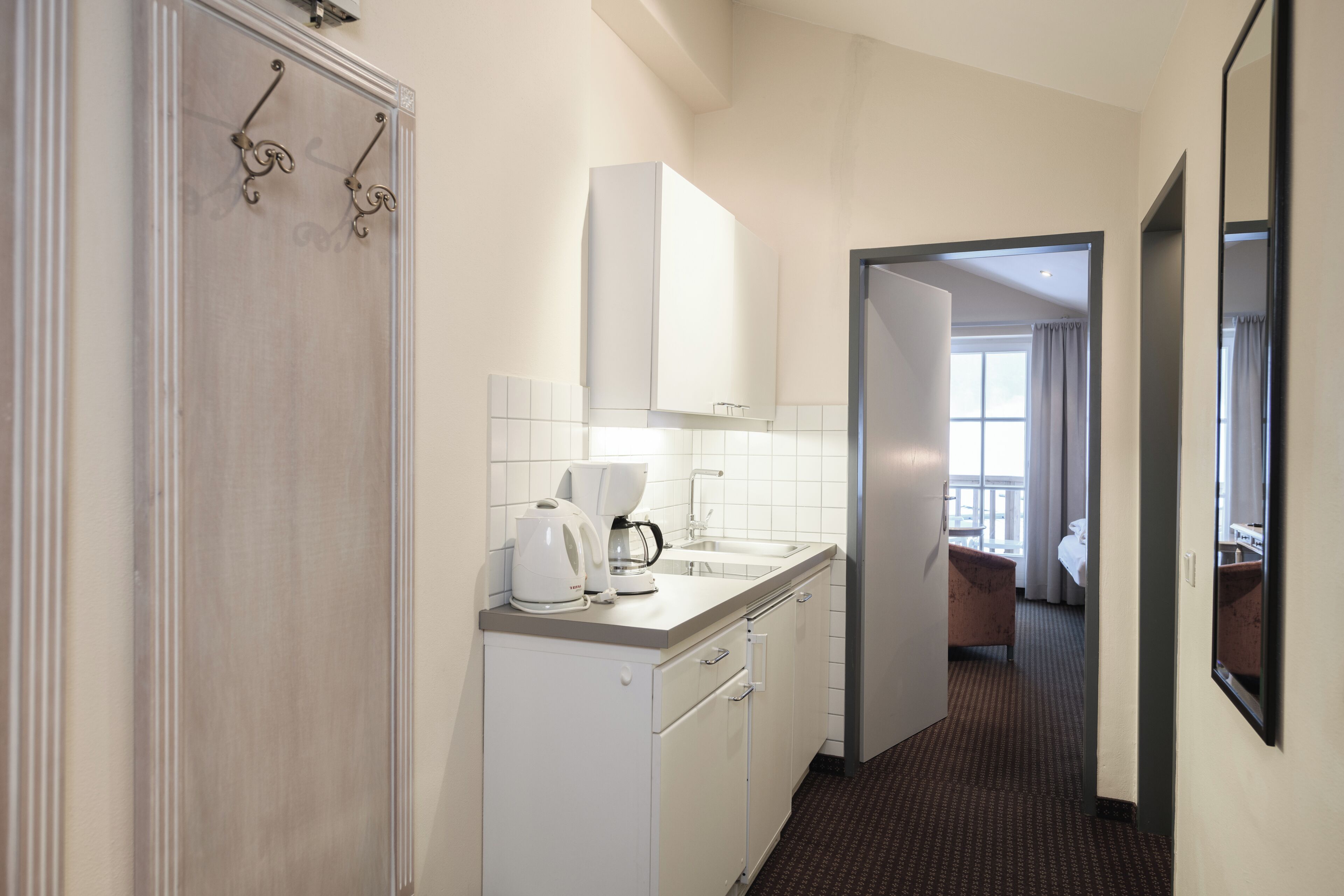 A hotel kitchen with a coffee maker, a sink, and cabinets.