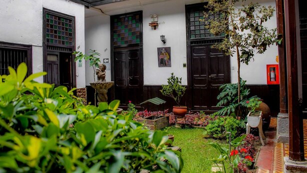 A courtyard with a small garden, potted plants, and a statue. - Hotel Casablanca (Cajamarca)