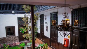 A courtyard with a patterned floor, potted plants, and a hanging chandelier. - Hotel Casablanca (Cajamarca)