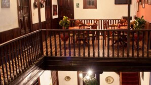 A multi-level hotel lobby with a dining area, staircase, and a plant in the center. - Hotel Casablanca (Cajamarca)