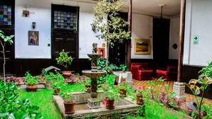 A courtyard with a central fountain, potted plants, and red furniture. - Hotel Casablanca (Cajamarca)