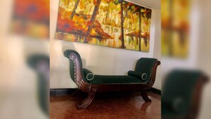 Una habitación con un banco de madera y un cuadro abstracto grande en la pared.