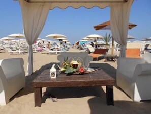 Un espace aménagé près de la plage, avec une table, des chaises et des parasols.