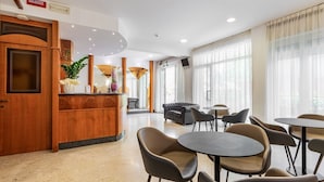 Hall dell'hotel con reception, area salotto e ampie finestre.