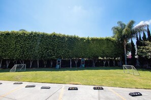 Ein Parkplatz mit drei Fußballtoren, einer Hecke und einer Palme.