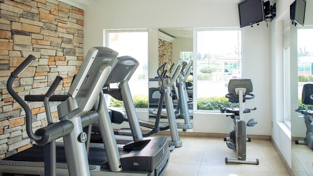 Un gimnasio con cintas de correr, una bicicleta estática y una máquina de remo.