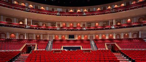 A multi-level auditorium with red seating and a central stage.