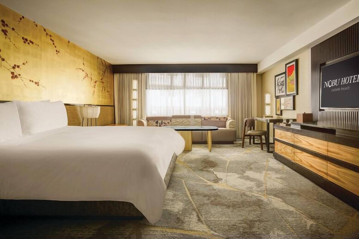 A hotel room with a large bed, a sofa, a desk, and a television.
