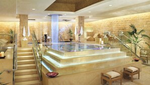 A luxurious spa area with a glass-enclosed hot tub, a staircase leading to a seating area, and a stone wall backdrop. - NOBU Las Vegas – A Caesars Rewards Destination (Las Vegas)
