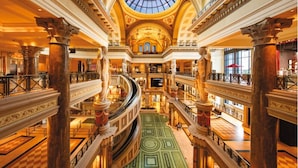A grand interior with multiple levels, ornate columns, and a central skylight. - NOBU Las Vegas – A Caesars Rewards Destination (Las Vegas)