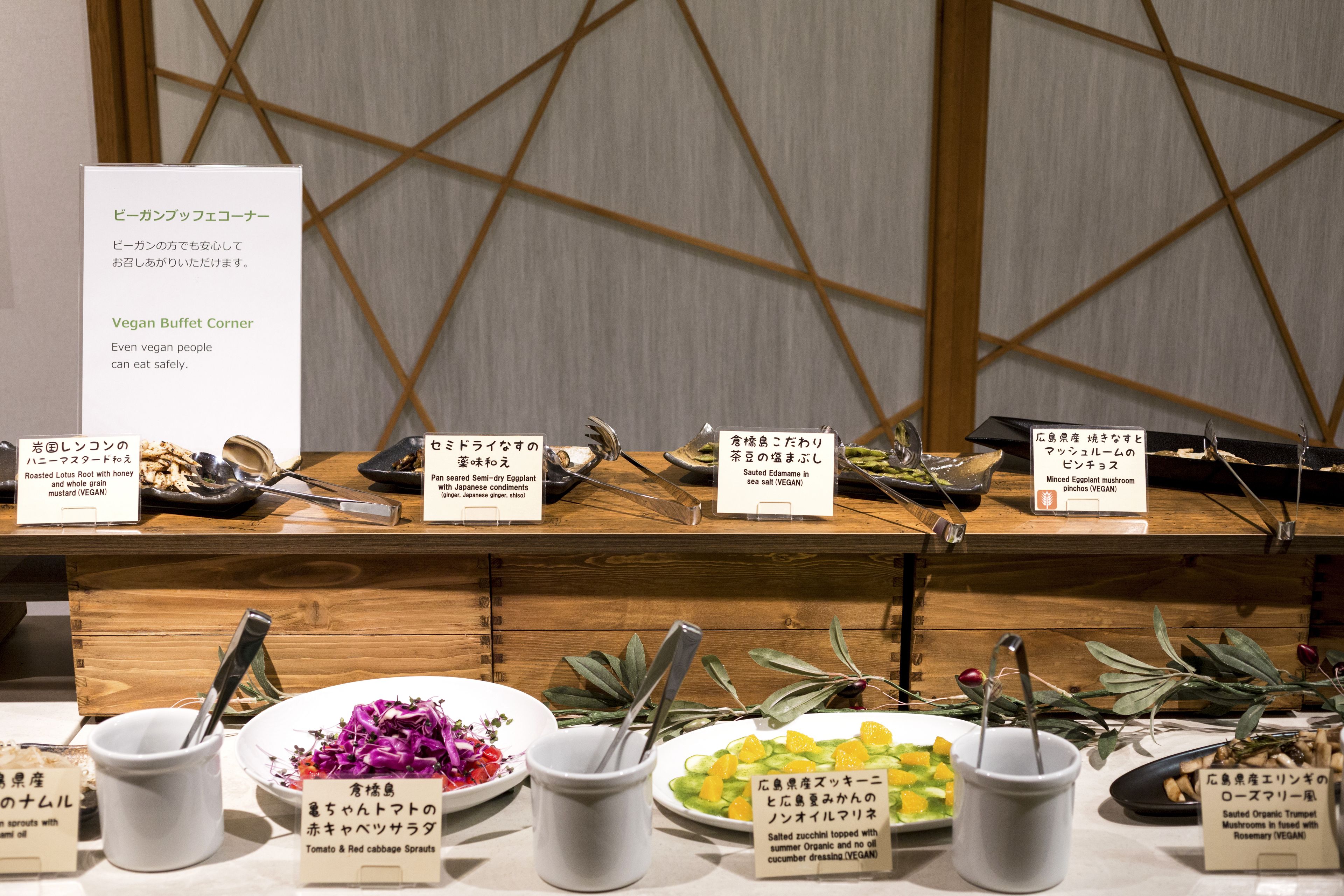 A buffet counter with various labeled dishes, including vegan options.