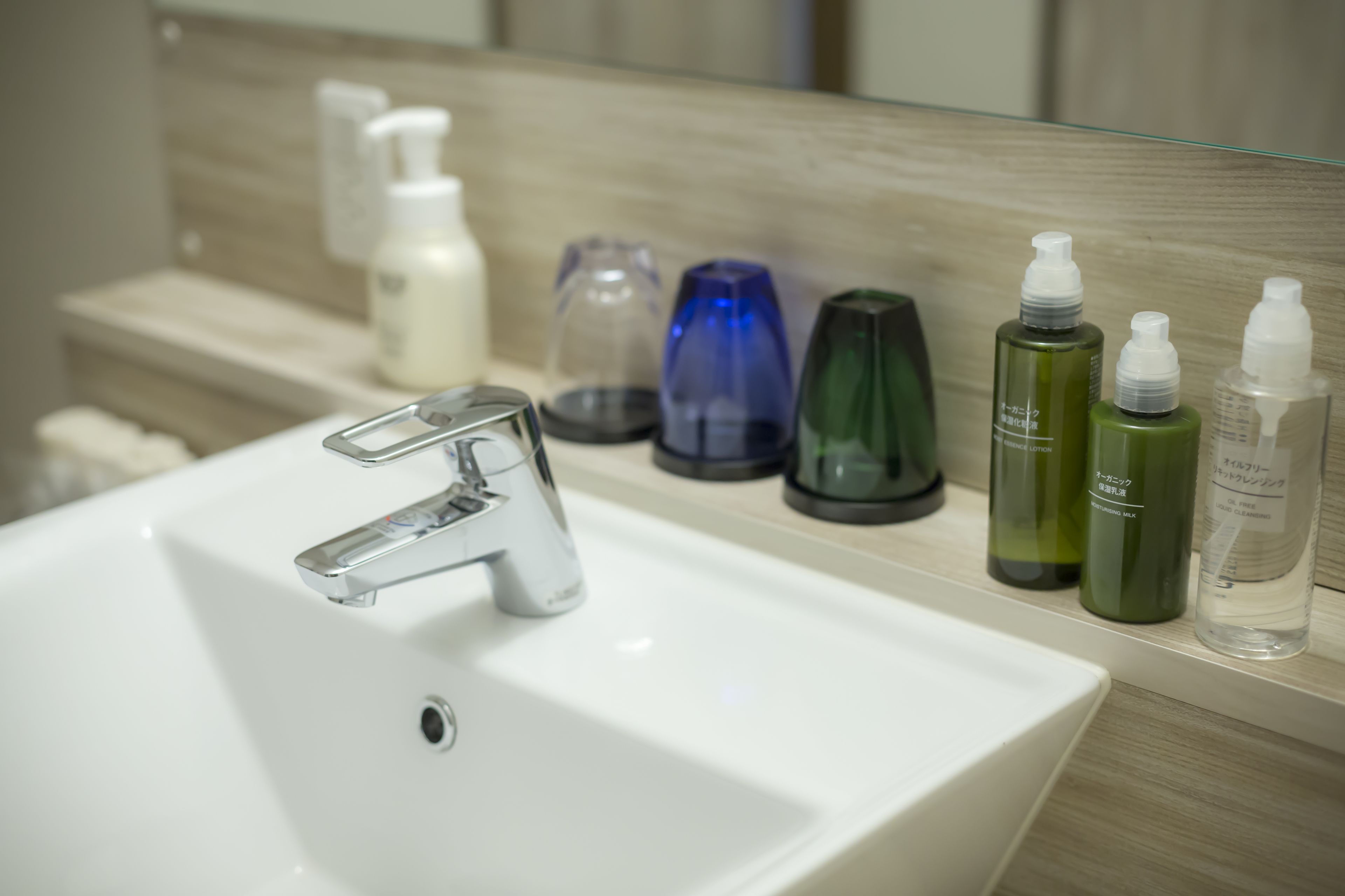 A bathroom sink with a modern faucet, a mirror above it, and various toiletries on the countertop.