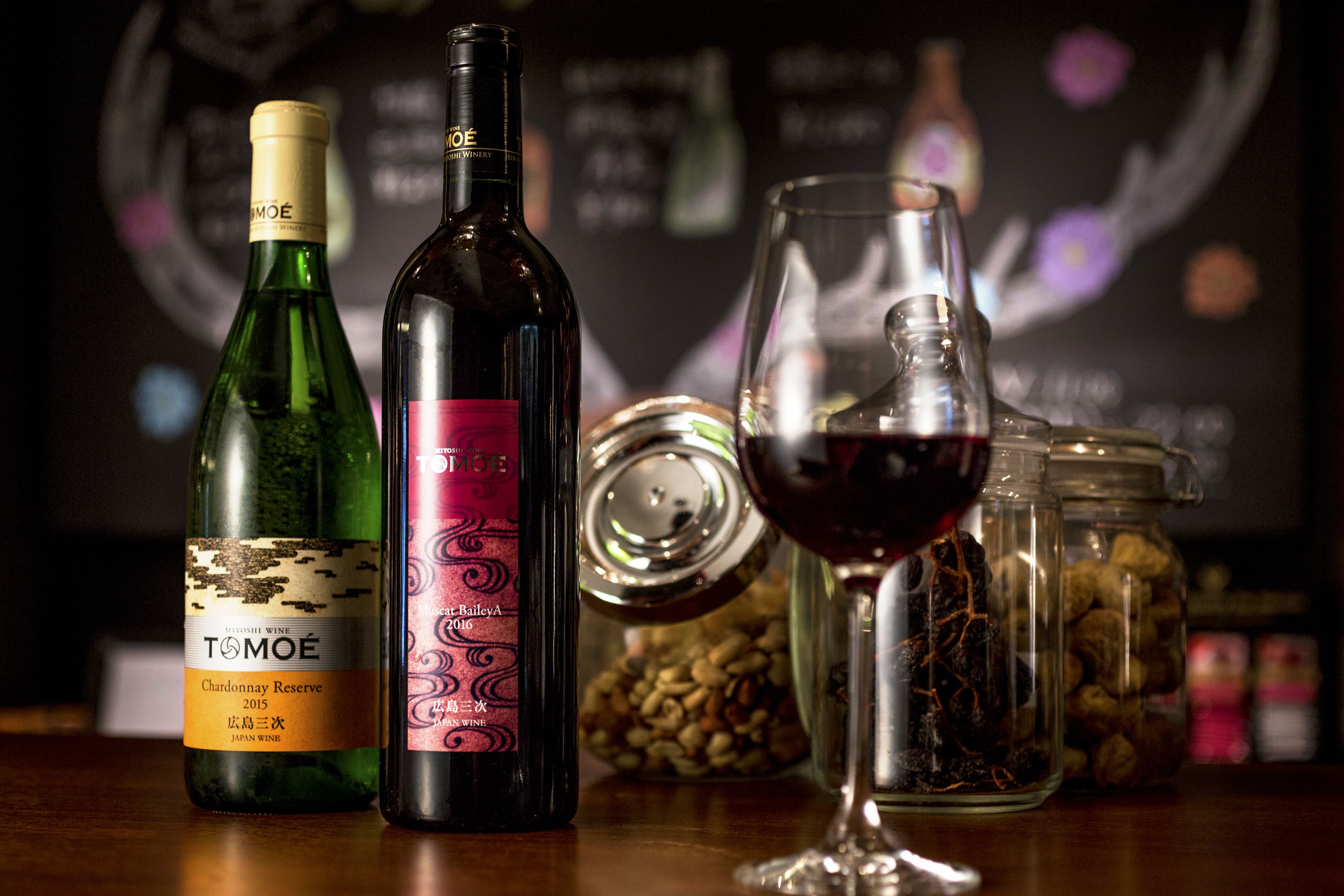 Duas garrafas de vinho e uma taça sobre uma mesa.