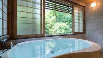 A large bathtub with a view of greenery through a window with a grid pattern.