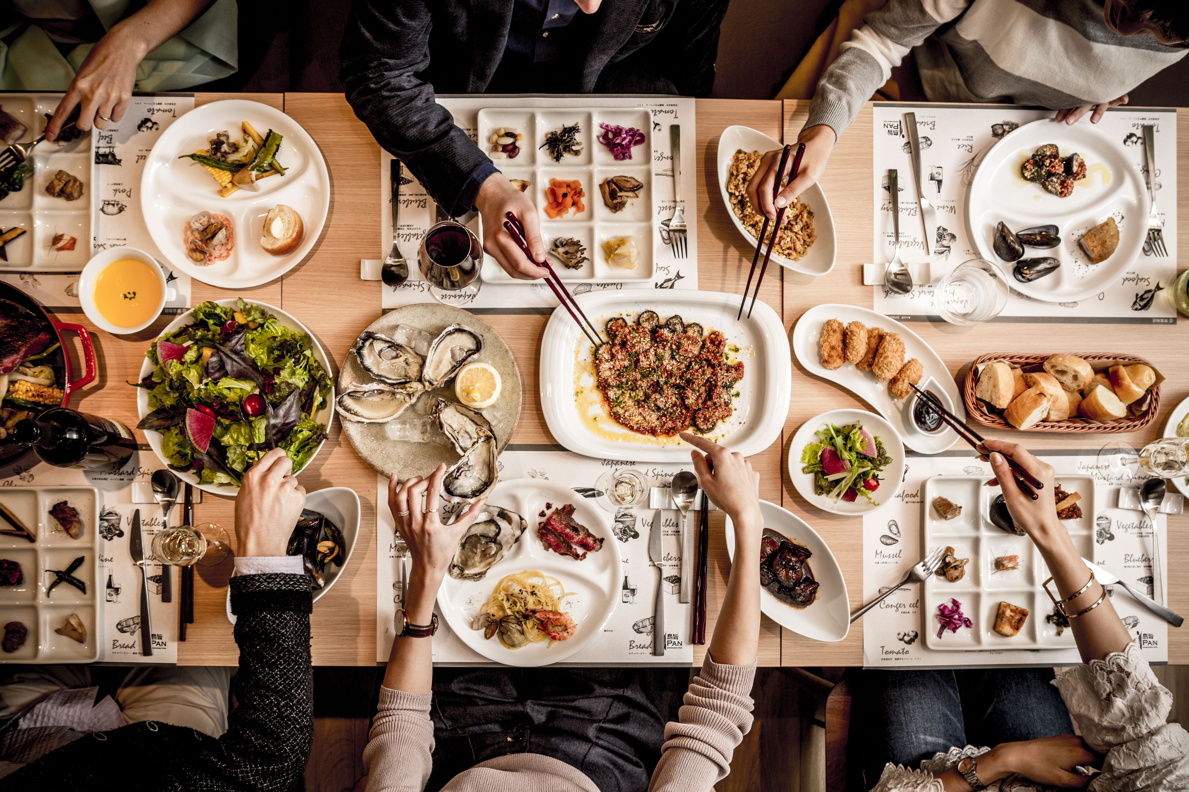 A dining table with multiple plates of food, utensils, and a menu.