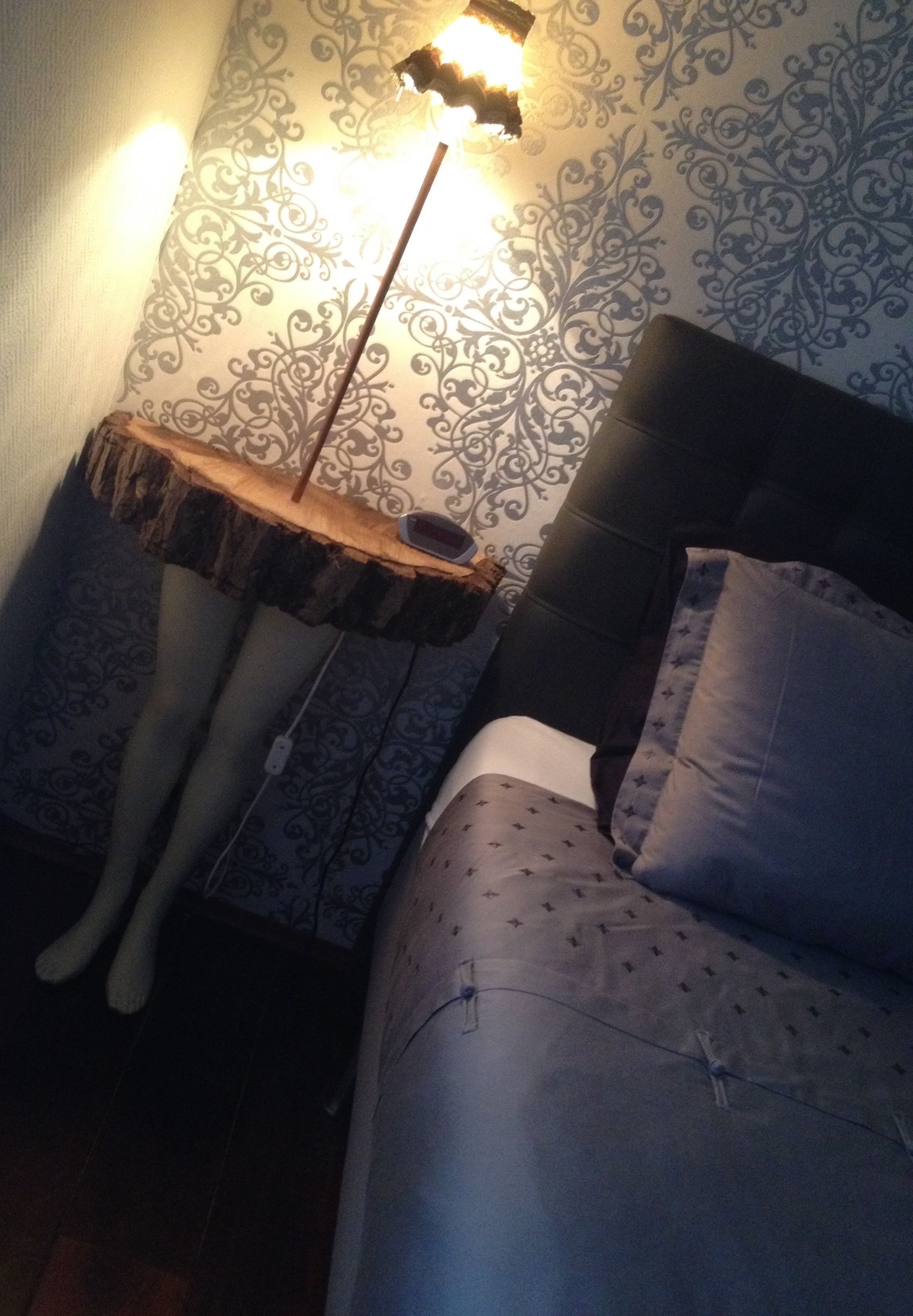 Een slaapkamer met een bed, een nachtkastje en een lamp.