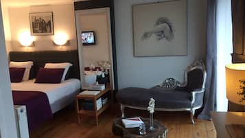 A hotel room with a bed, a chair, a small table, and a mirror.