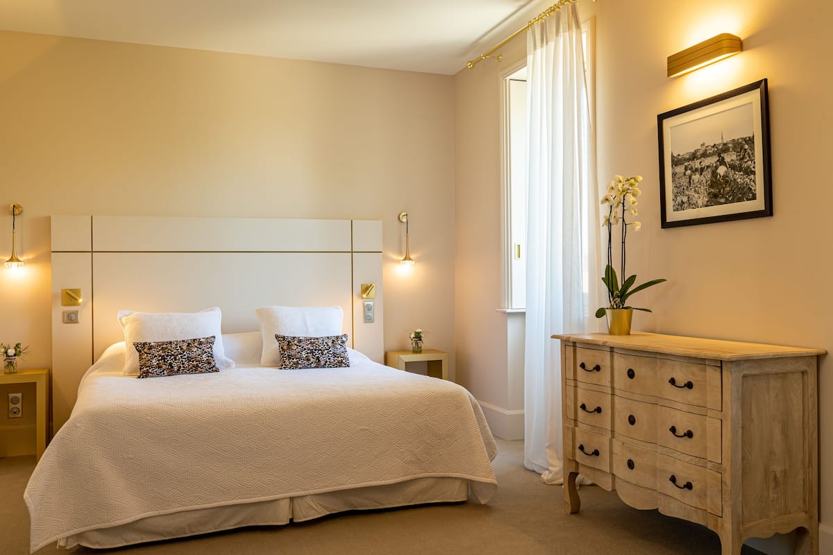 Ein Schlafzimmer mit einem großen Bett, Nachttischen, einer Kommode und einem gerahmten Bild an der Wand.