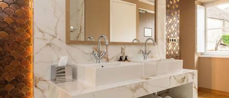 Un baño con dos lavamanos, un espejo, un perchero para toallas y un detalle decorativo en la pared.