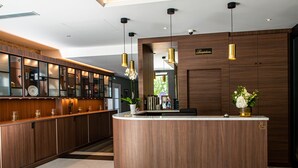 A modern reception area with a curved wooden counter, glass display cabinets, and pendant lighting. - Olivier leflaive (Puligny-Montrachet)