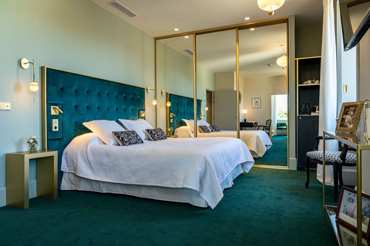 Ein Hotelzimmer mit einem großen Bett, einem Spiegel und einem kleinen Tisch.