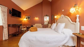 A bedroom with a large bed, a desk, a chair, a lamp, and wall sconces.