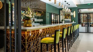 A bar area with a modern design, featuring a bar counter, seating with yellow chairs, and decorative plants. - Olivier leflaive (Puligny-Montrachet)