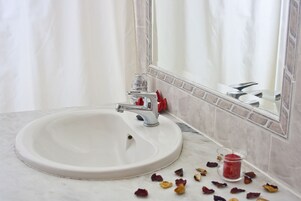 Et badeværelse med en hvid vask, et spejl og et flisebeklædt backsplash.