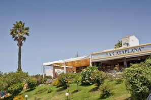 A building with a sign reading "A CATAPLANA" and a covered outdoor area with a palm tree and various plants. - Alte Hotel (Loulé)