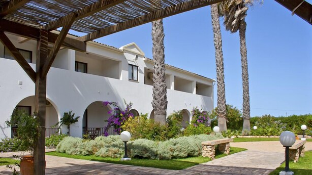 A modern building with a white facade, multiple balconies, and a landscaped garden with palm trees and shrubs. - Alte Hotel (Loulé)