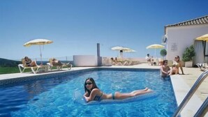 A swimming pool with lounge chairs and umbrellas, surrounded by a clear sky. - Alte Hotel (Loulé)