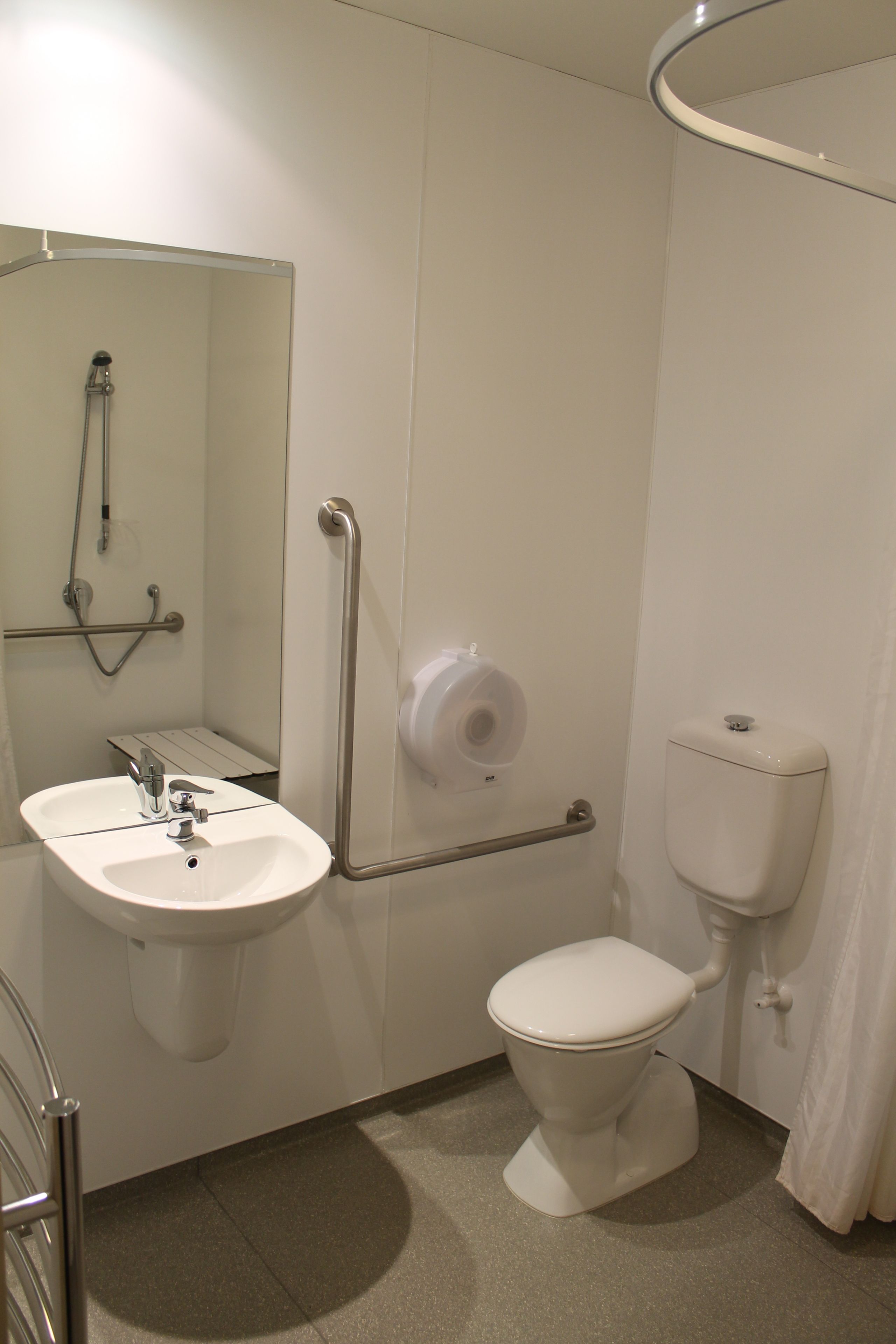 Ein modernes Badezimmer mit Waschbecken, Toilette und Dusche, alles in Weiß.