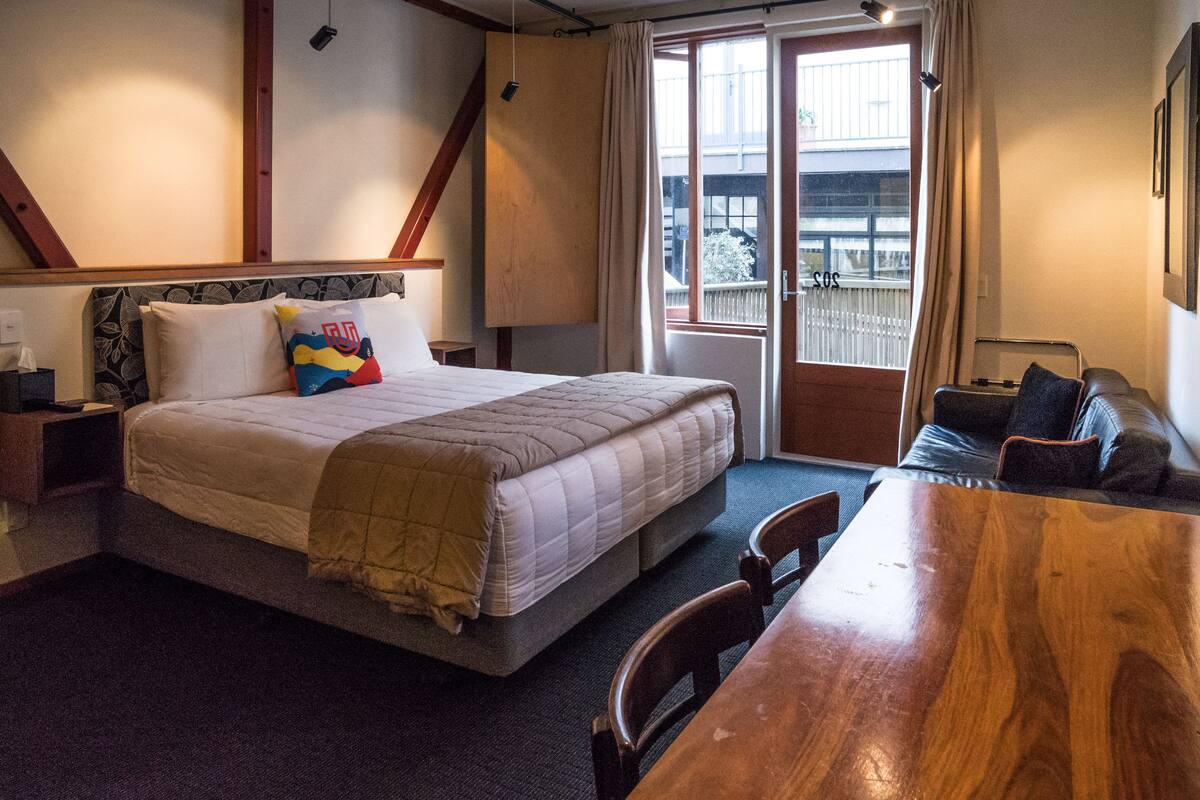 A hotel room with a bed, a wooden dining table, and a sofa.